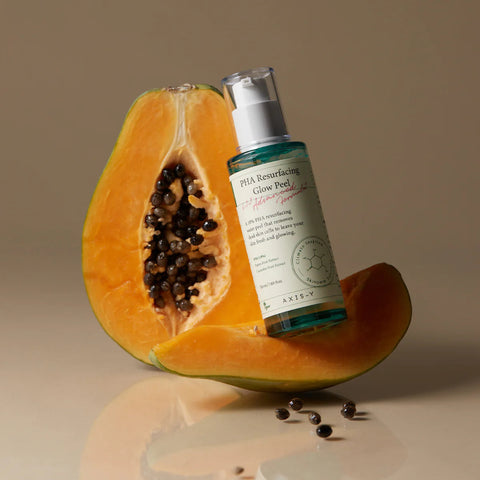Axis-Y PHA Resurfacing Glow Peel bottle against two halves of a papaya fruit.